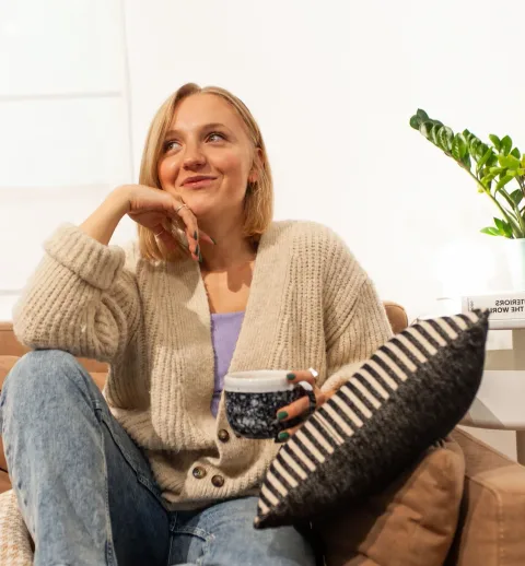 Zufriedene Psychotherapeutin entspannt nach der Sitzungsdokumentation mit einer Tasse auf dem Sofa.