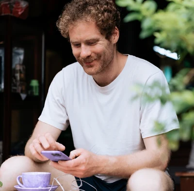 Ein Psychotherapeut entspannt nach dem Praxisalltag mit seinem Smartphone bei einer Tasse Kaffee.