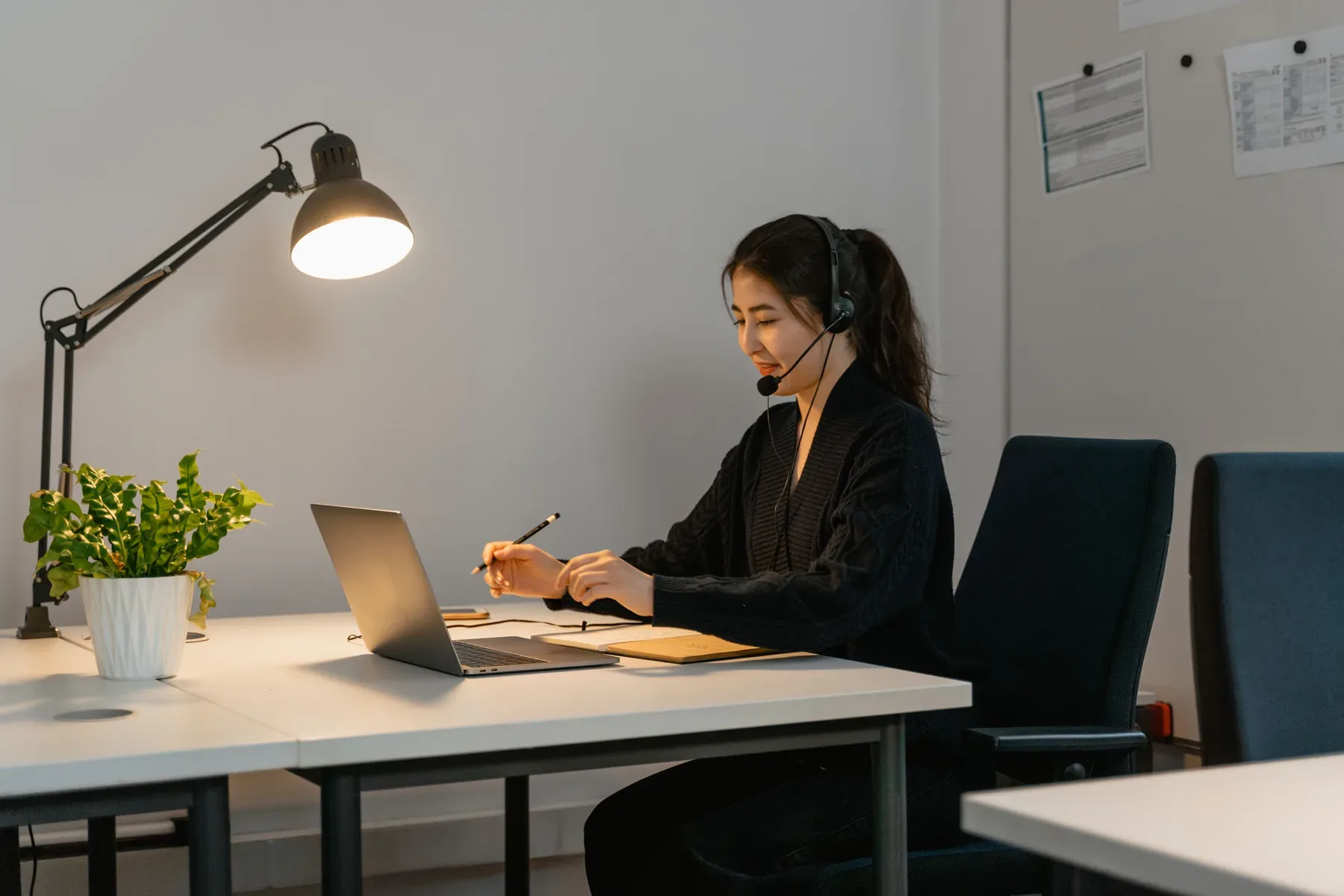 Frau mit Headset arbeitet an einem Laptop.